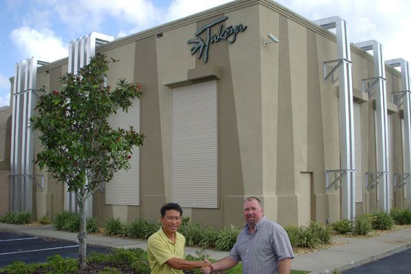 Two men shaking hands in front of a building with the word 
