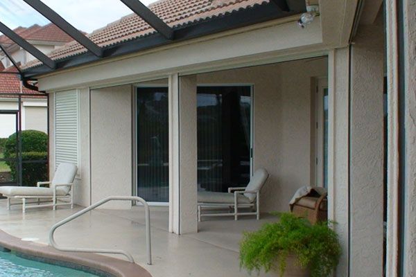 Patio with pool, lounge chairs, and potted plant. Open sliding glass door.