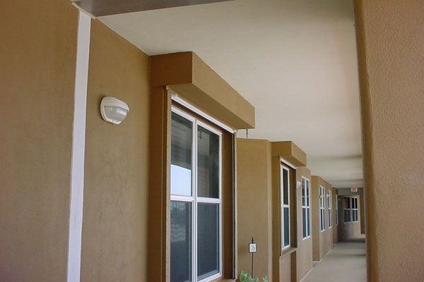 Exterior hallway with windows and light-colored walls and ceiling, brown trim.