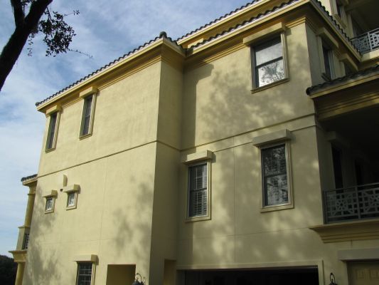 Beige stucco building with windows and a garage door, under a blue sky.