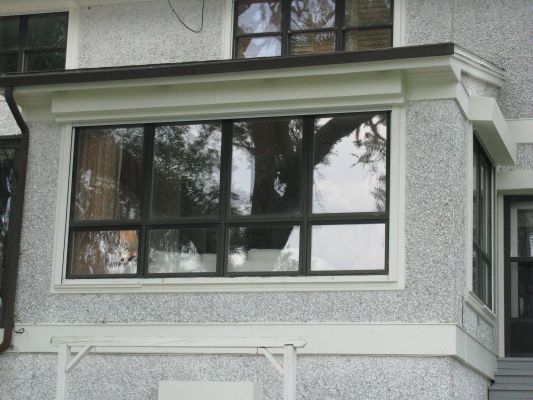 A large window with black frames set into a stucco wall.
