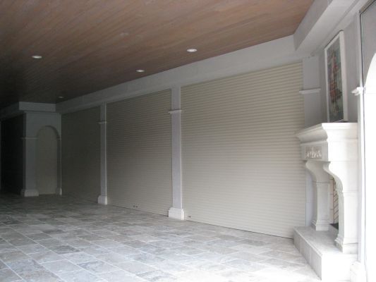 Interior with beige roller shutters, ornate pillars, fireplace, and stone flooring.