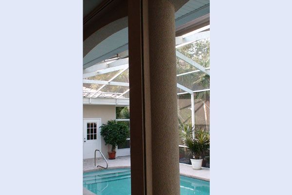 View through a window of a pool area with a column on the right side.