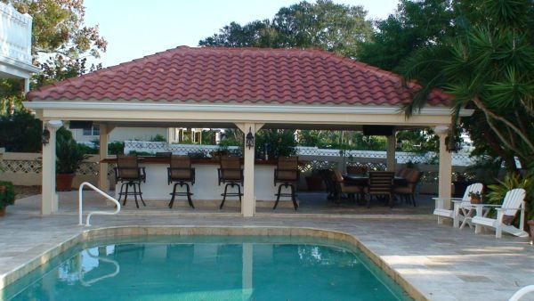 Poolside outdoor bar with red tile roof, bar stools, tables, and a swimming pool.