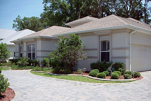 Tan stucco house with driveway and landscaping.