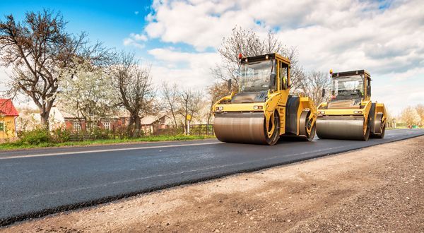 Two asphalt rollers are working on a new road.