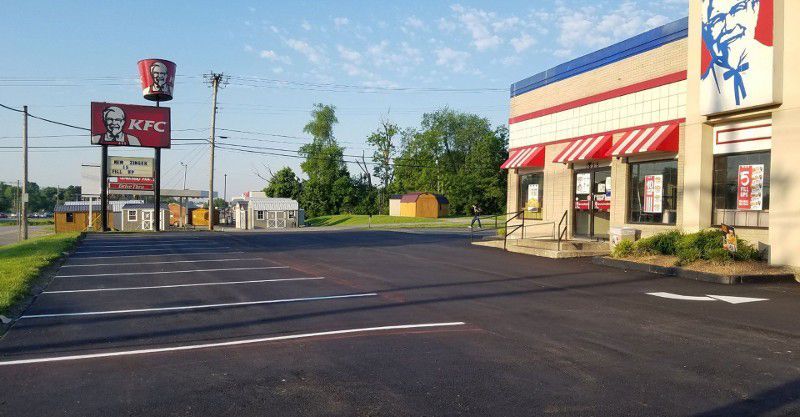A kfc restaurant with a parking lot in front of it.