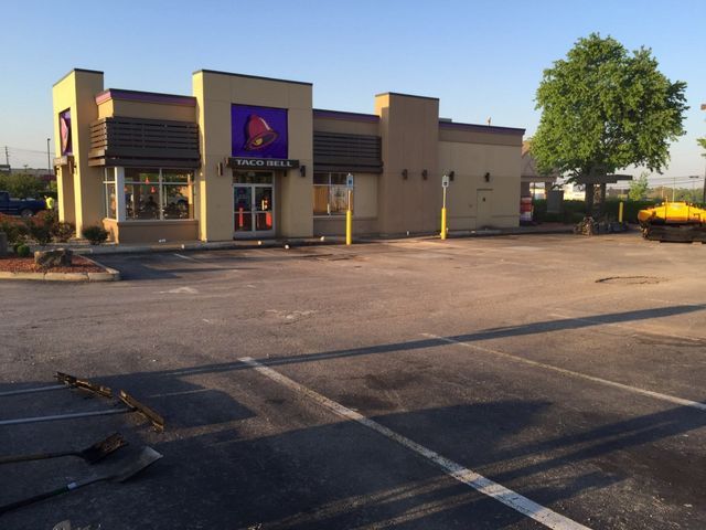 A taco bell restaurant with a parking lot in front of it