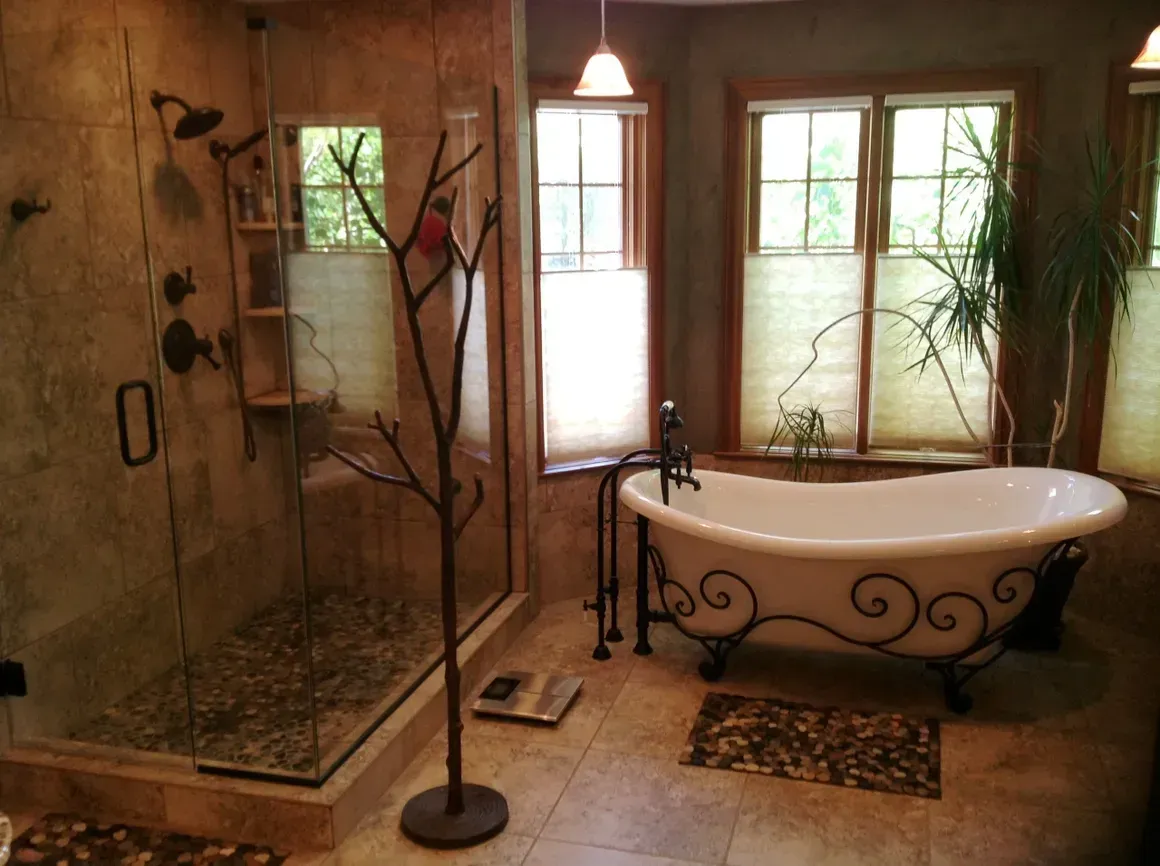 A bathroom featuring a walk-in stone shower, a clawfoot tub with ornate iron legs, and a freestanding coat rack.