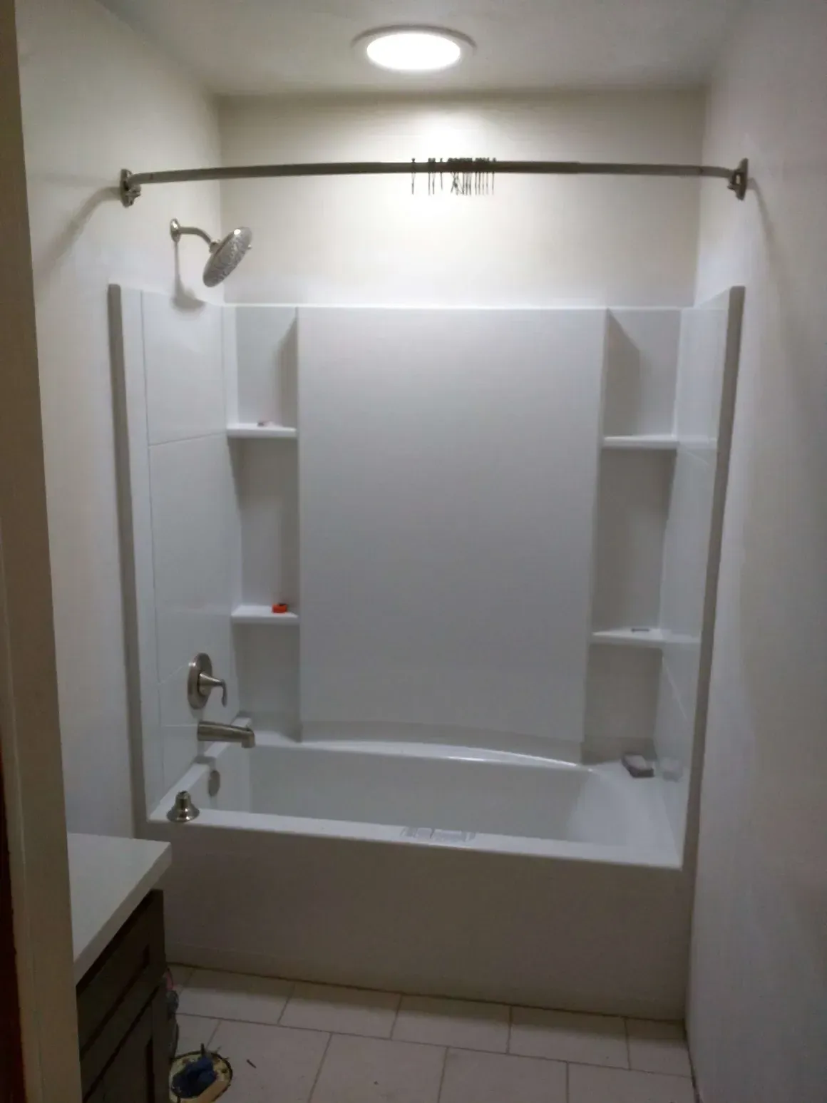 White bathtub and shower surround with a brushed nickel faucet and curved shower curtain rod in a bathroom.