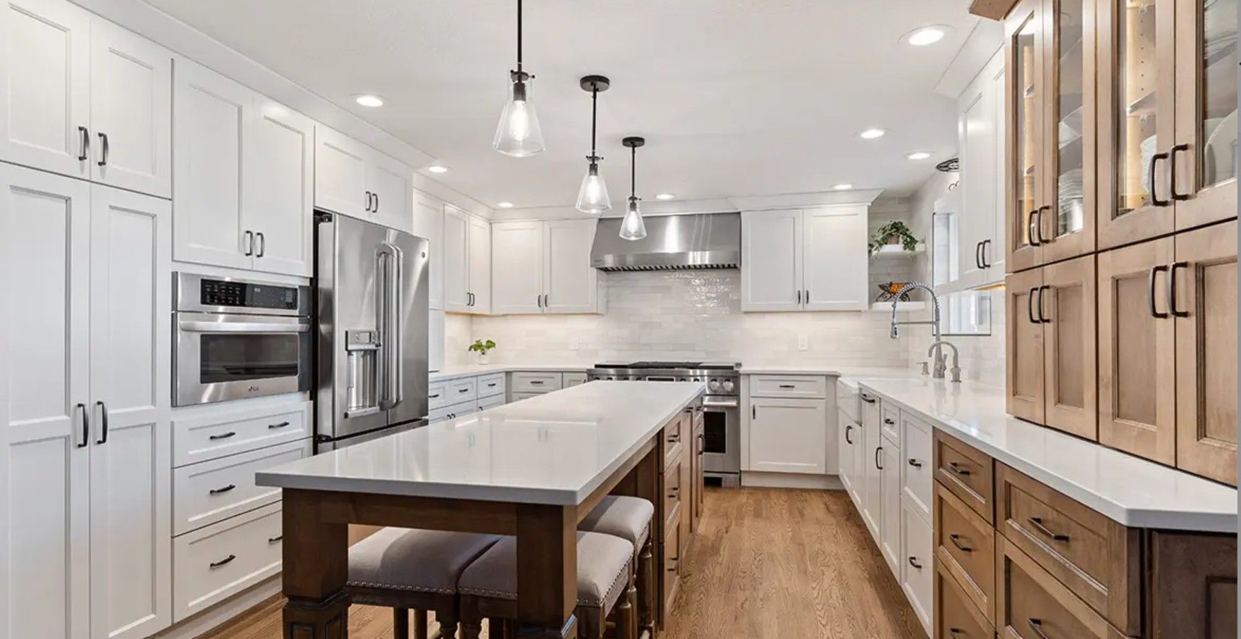 Bright modern kitchen with white cabinets, marble island, stainless appliances, and wood accents