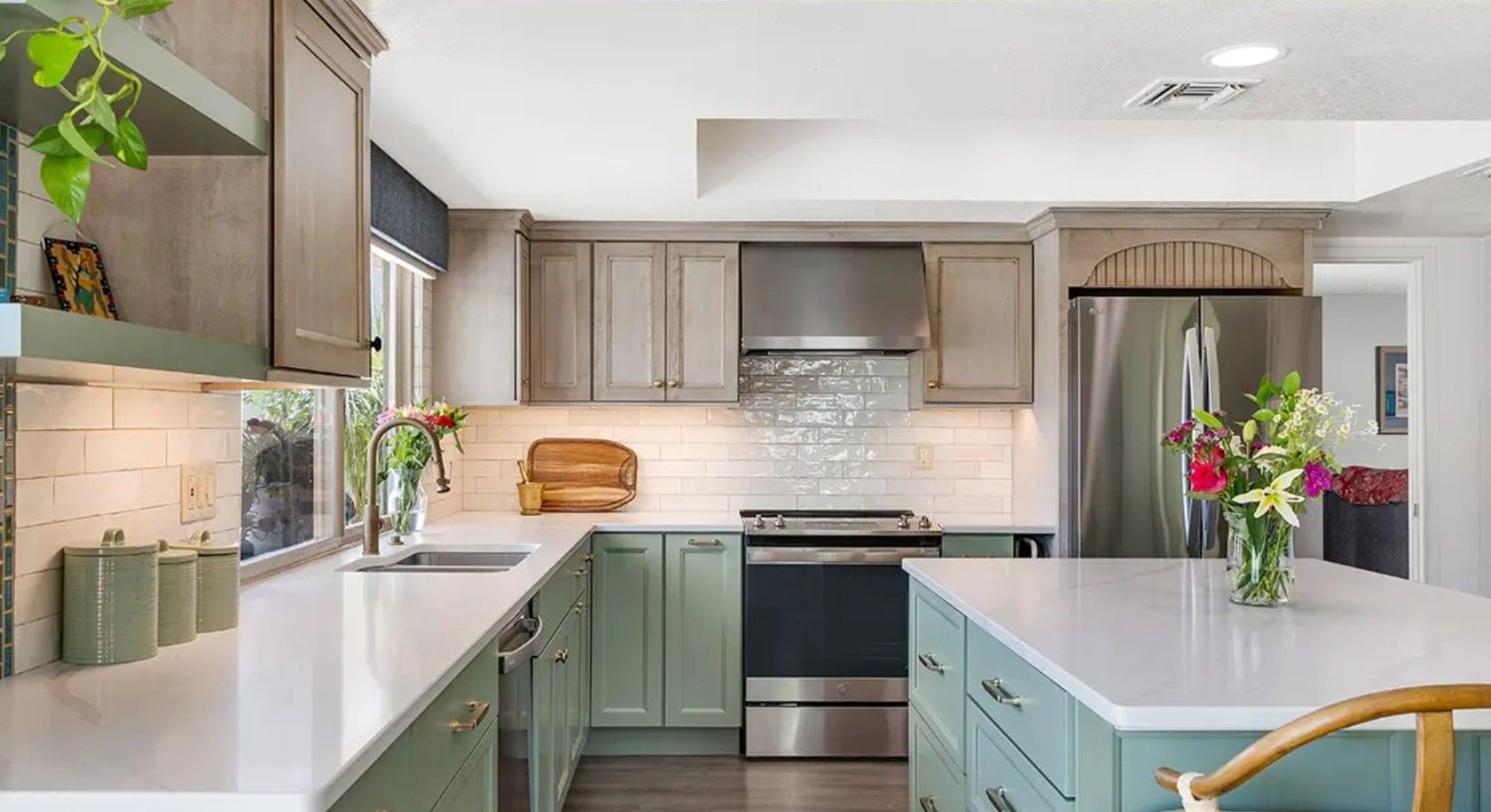Bright modern kitchen with white counters, mint cabinets, stainless appliances, and flowers by the window
