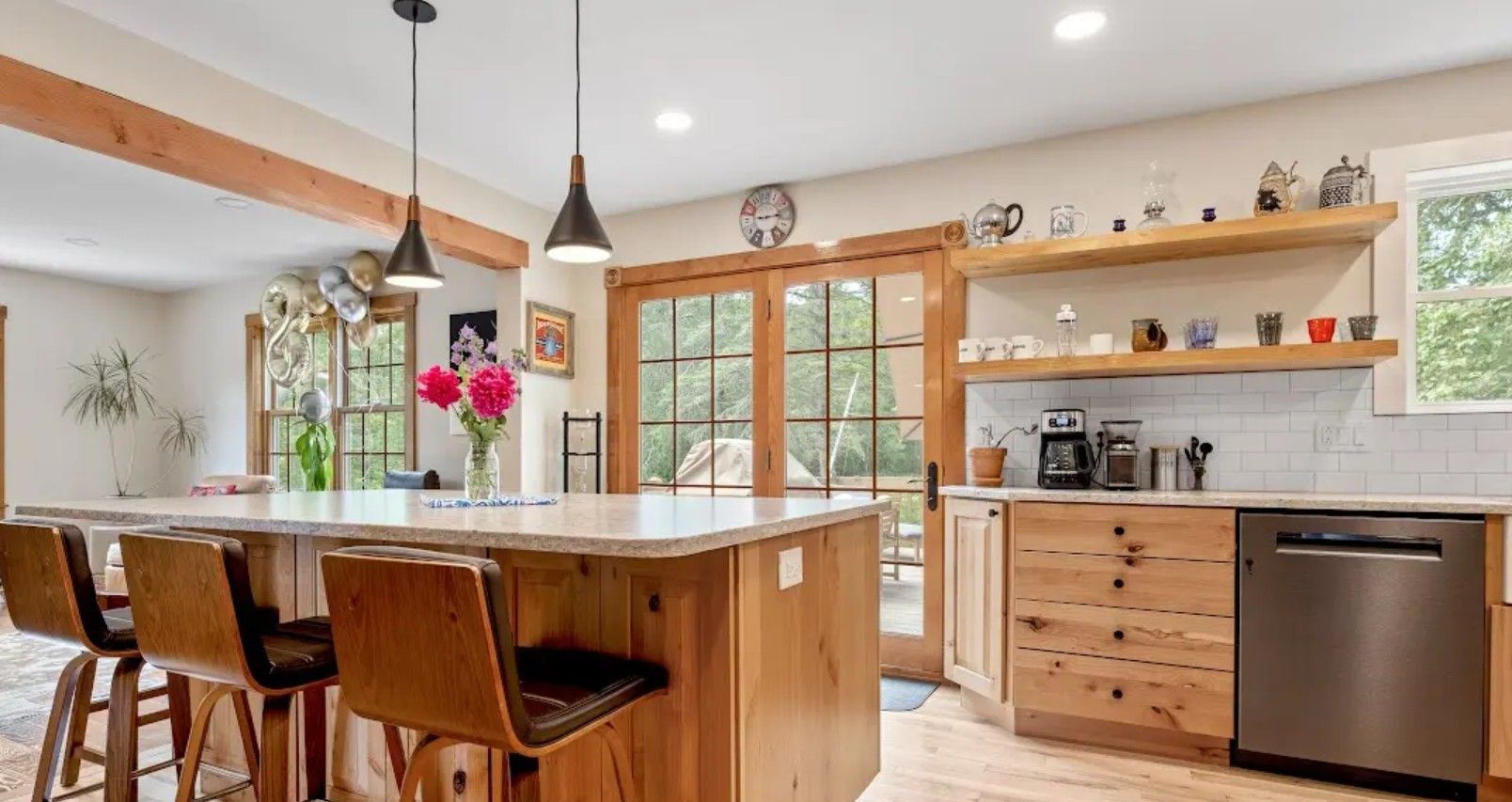 Bright modern kitchen with wood island, pendant lights, stainless appliances, and glass doors to a patio