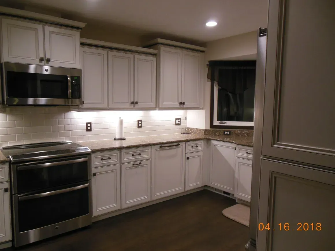A kitchen with white cabinets, stainless steel appliances, and a tiled backsplash.