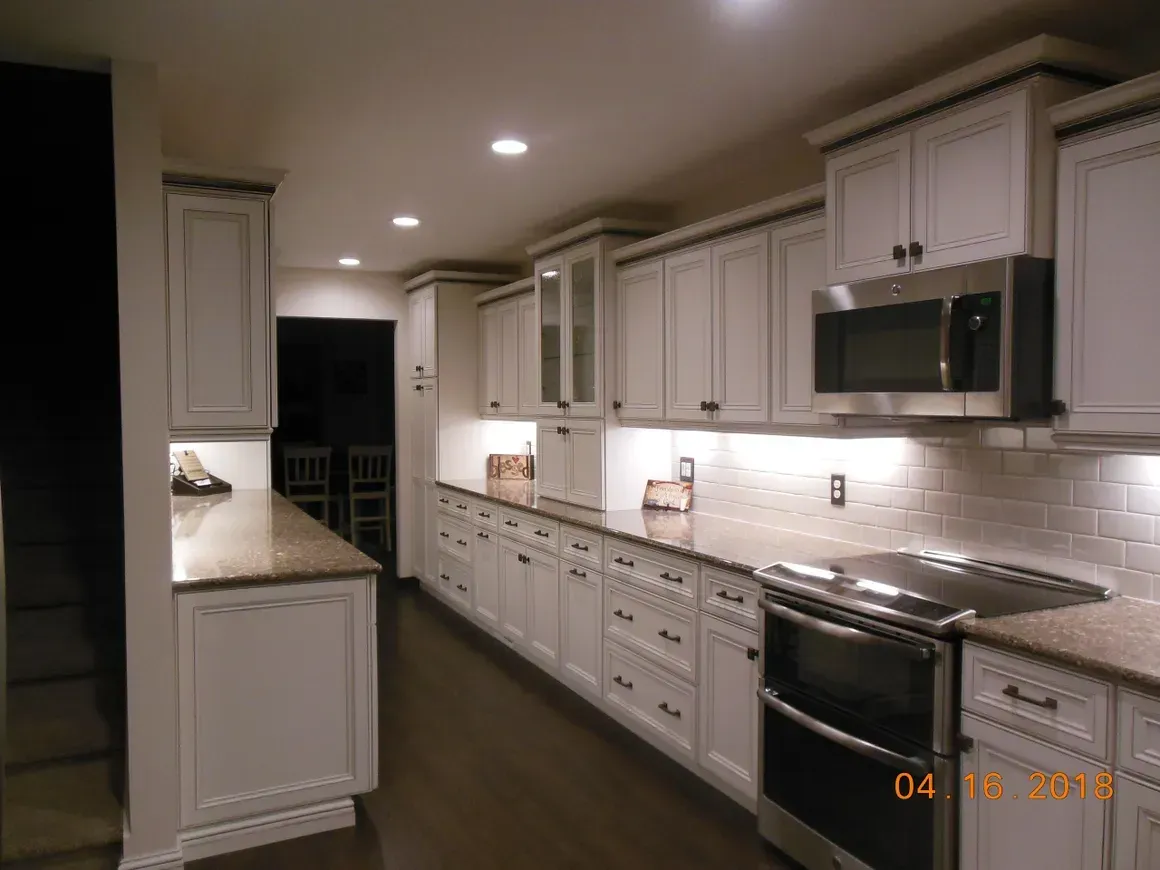 A modern, well-lit kitchen with white shaker cabinets, granite countertops, stainless steel appliances, and tile backsplash.