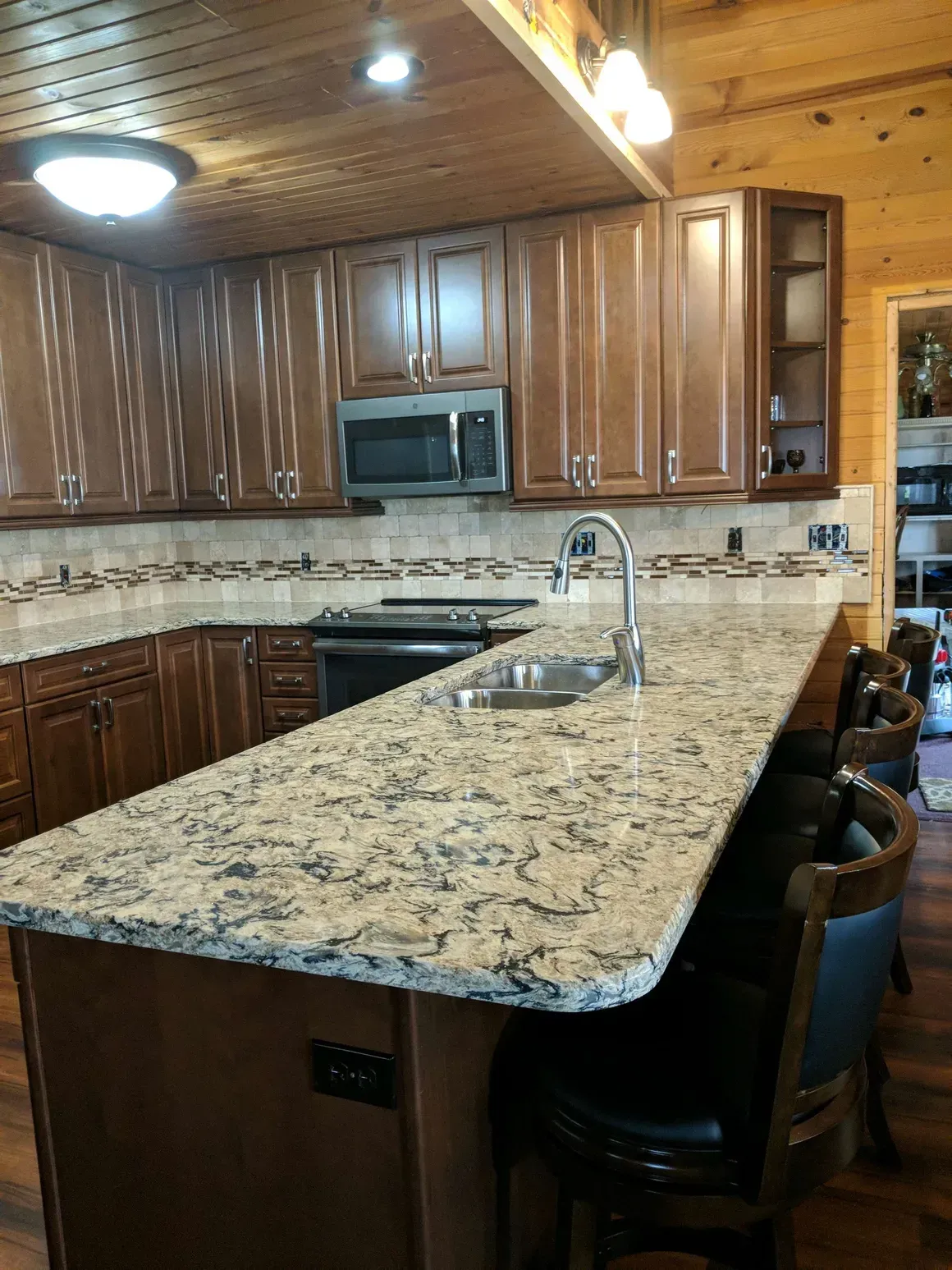 Kitchen with wood cabinets, granite countertops, a center island with bar stools, and a tile backsplash.