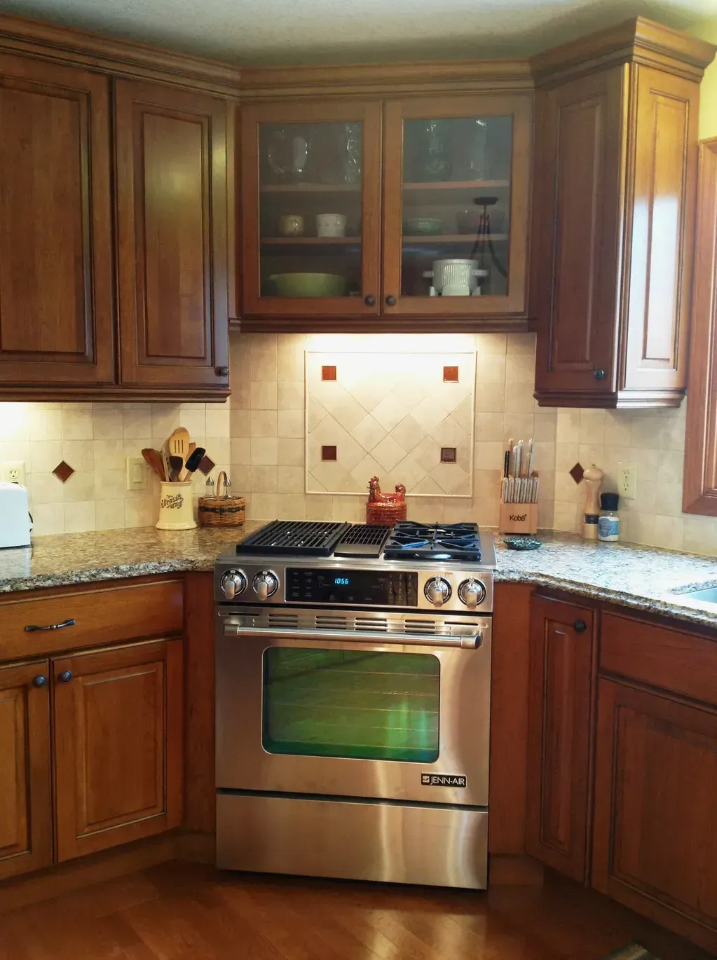 Stainless steel range nestled between cherry wood cabinets and granite countertops in a kitchen with tiled backsplash.