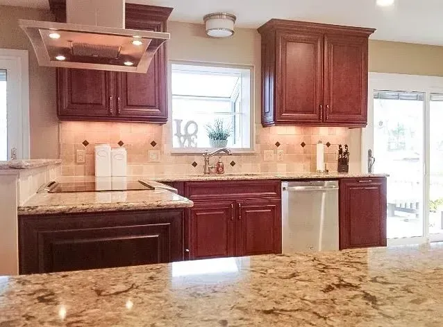 A modern kitchen featuring rich cherry-stained wood cabinets, granite countertops, and stainless steel appliances.