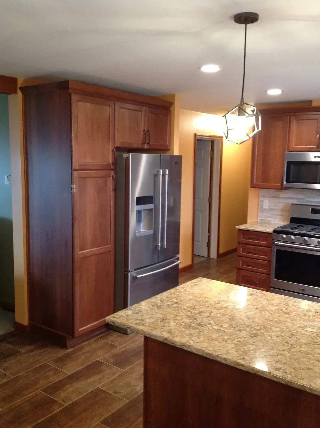 A modern kitchen featuring wooden cabinets, stainless steel appliances, granite countertops, and a central island.