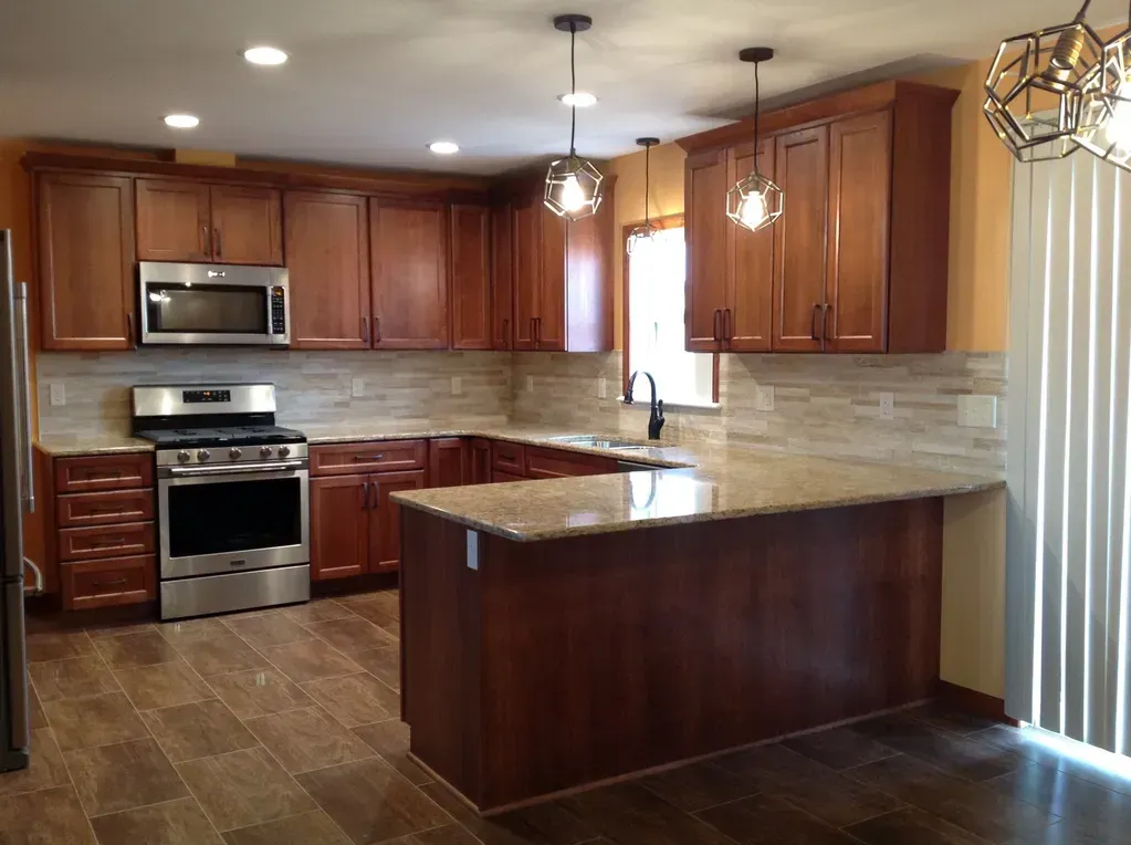 A kitchen with cherry wood cabinets, granite countertops, stainless steel appliances, and tiled floors.