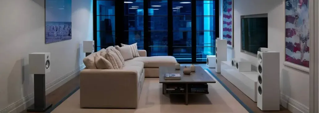 Modern living room with beige sofa, coffee table, TV, and floor-to-ceiling windows overlooking a city view