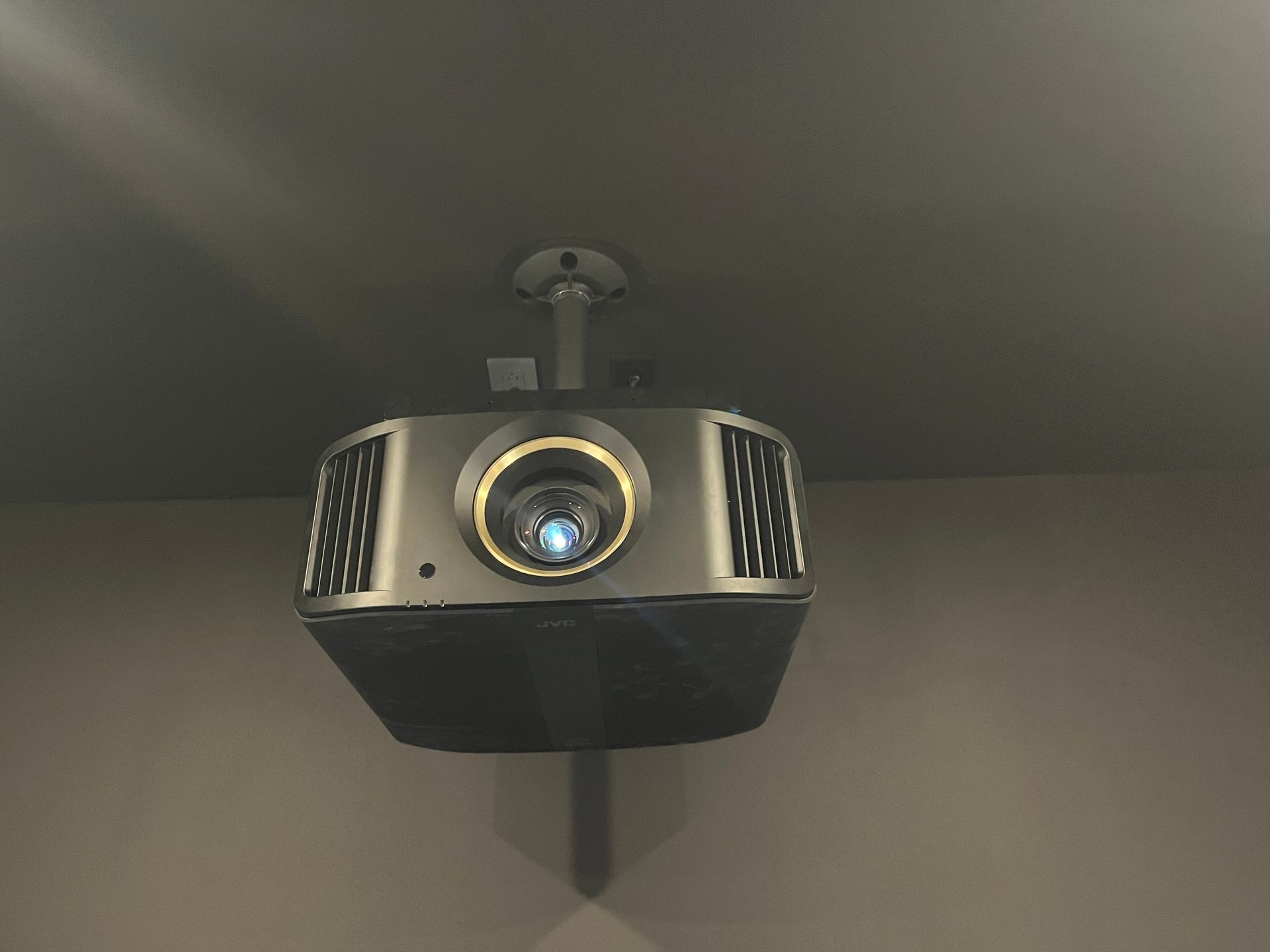 A projector is hanging from the ceiling in a dark room.