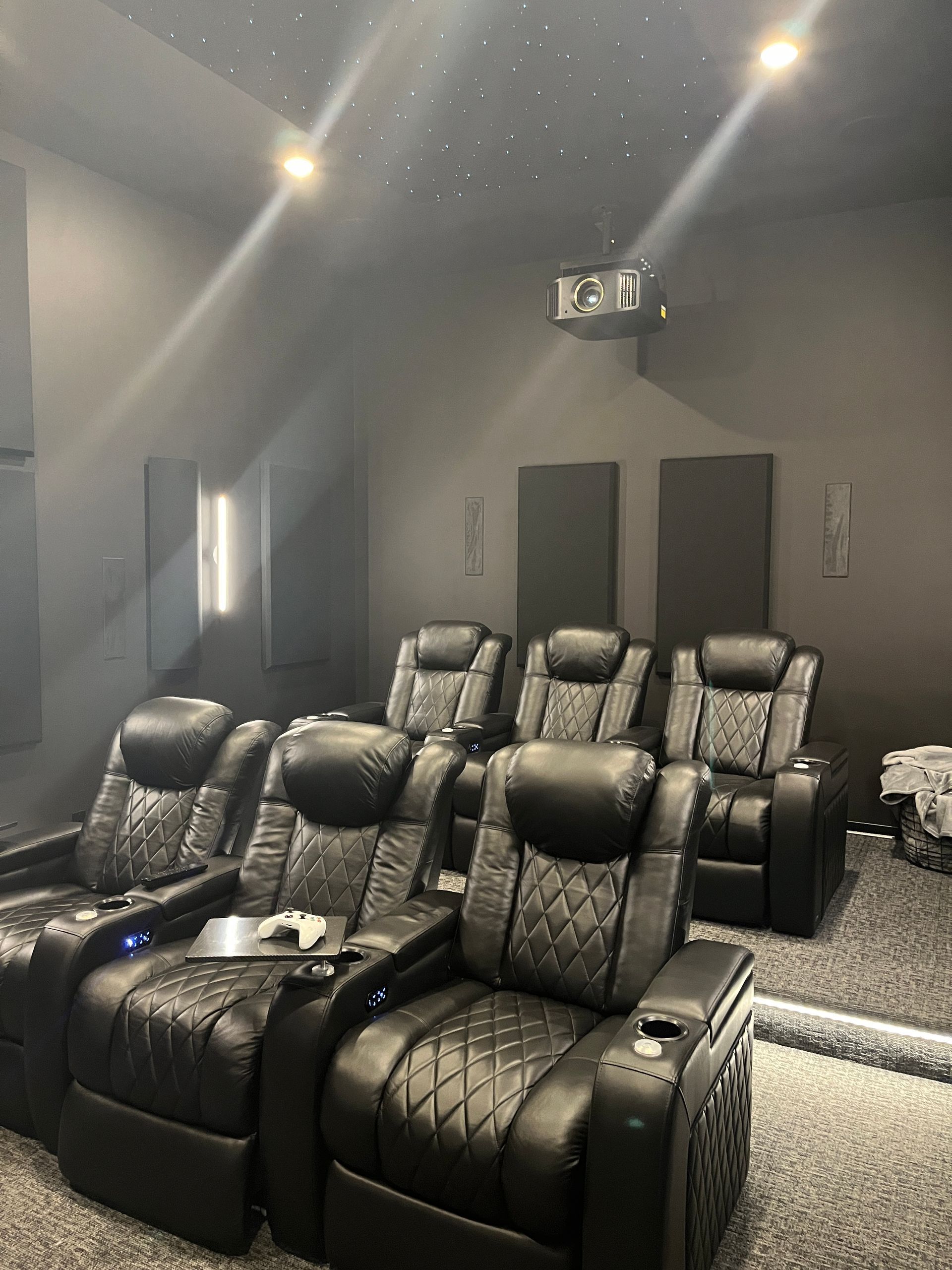 A home theater with a lot of black chairs and a projector.