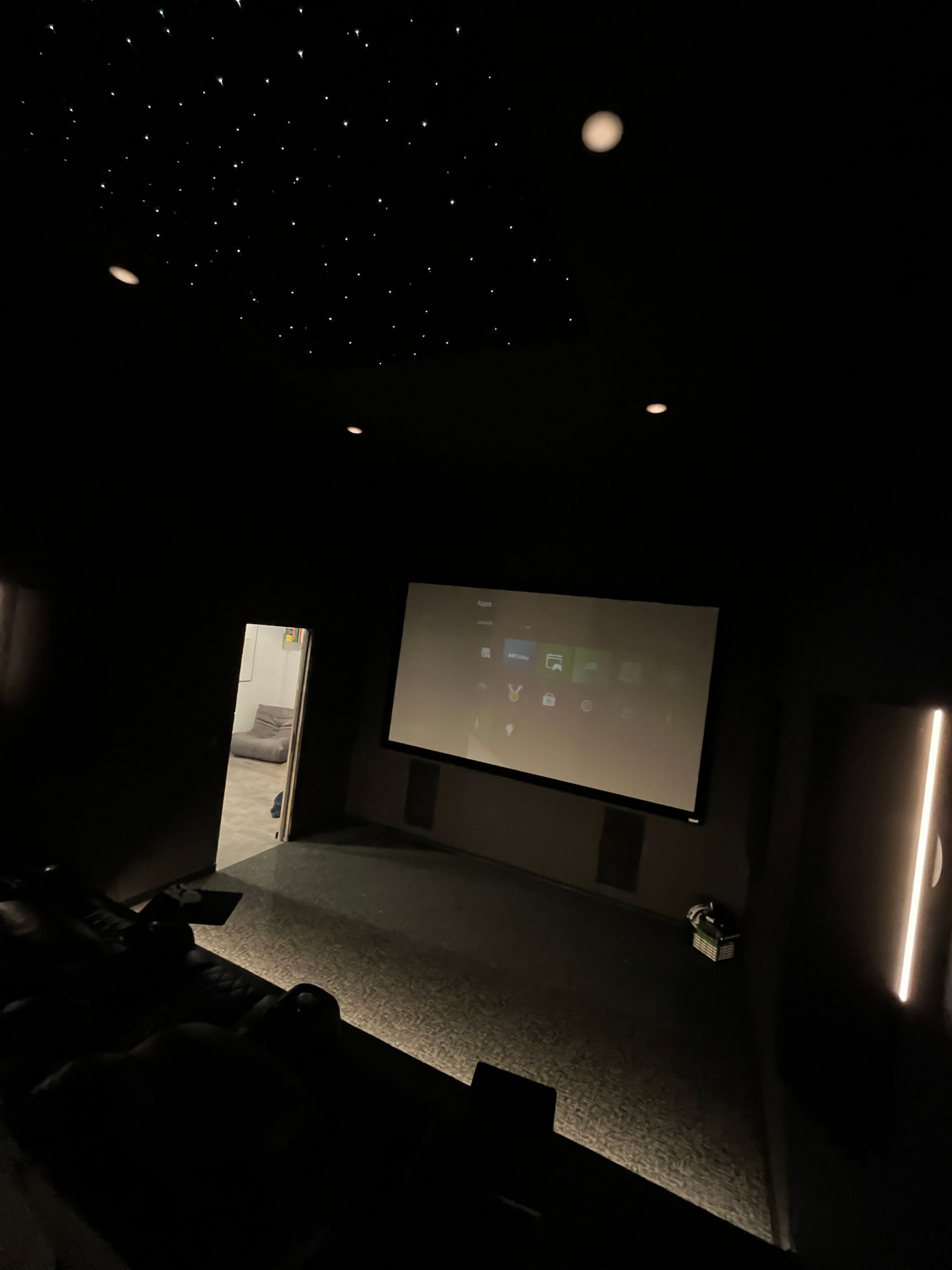 A dark room with a projector screen and stars on the ceiling
