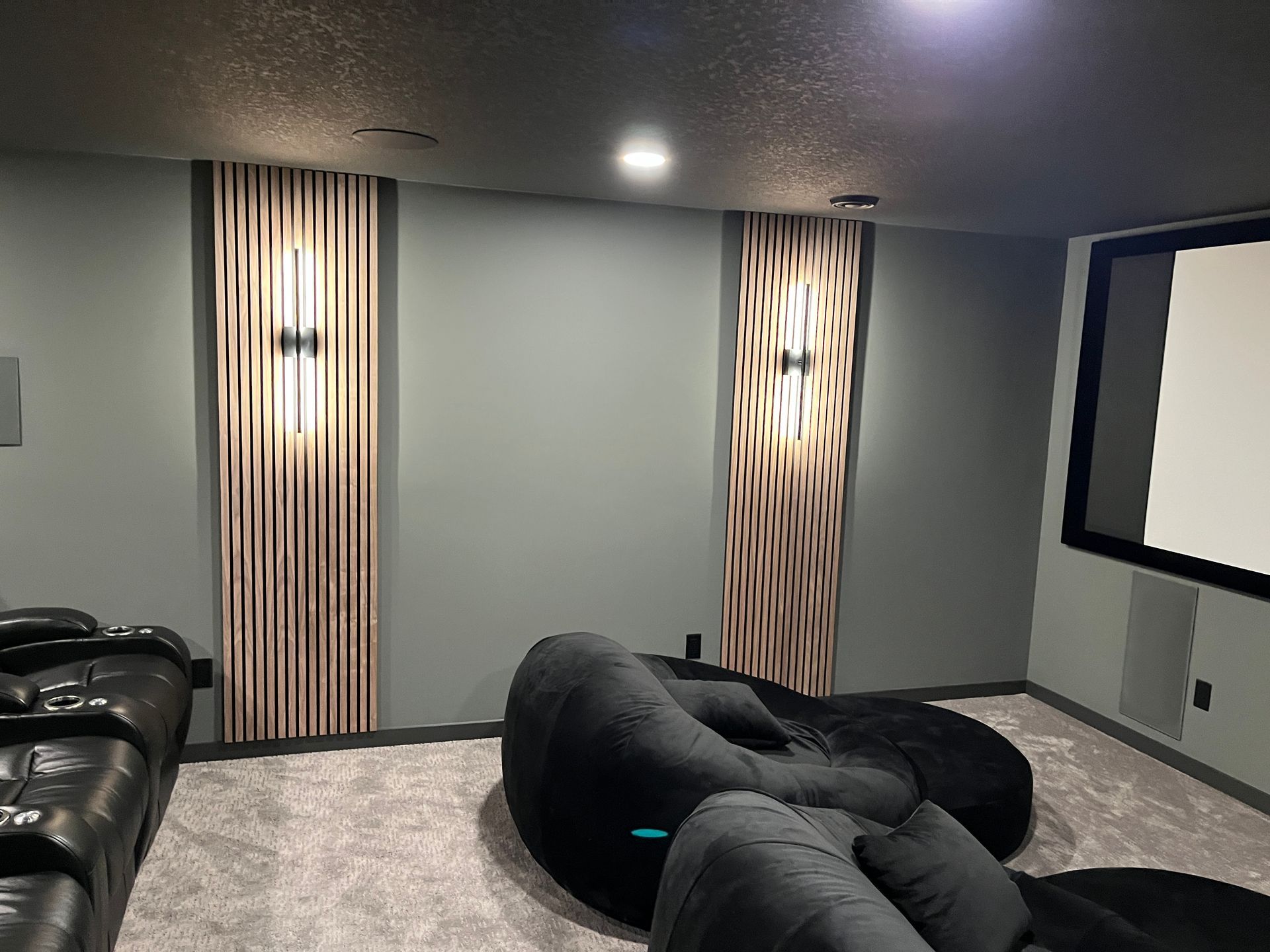A home theater with a couch , bean bag chairs , and a projector screen.