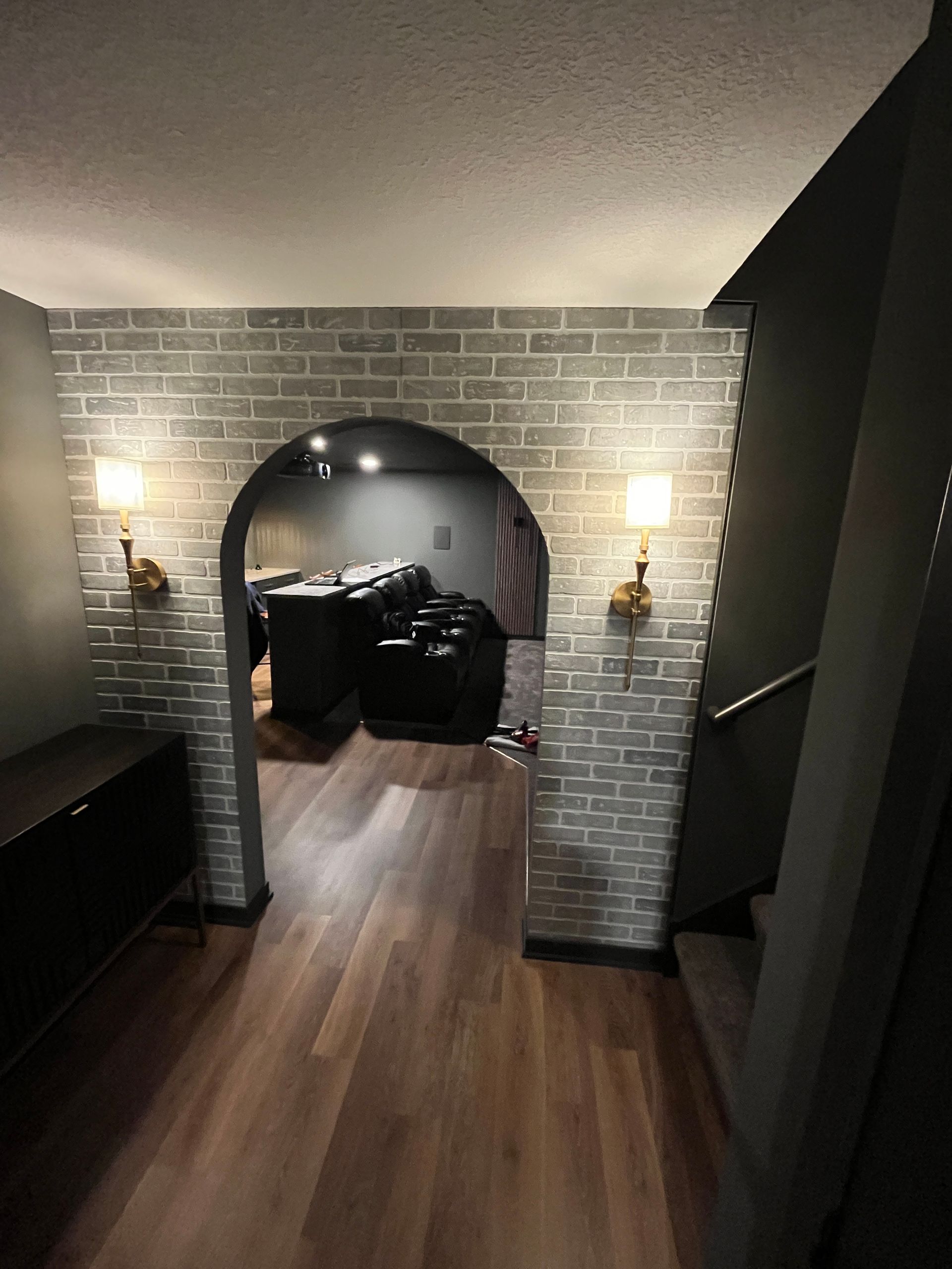 A hallway with a brick archway leading to a living room