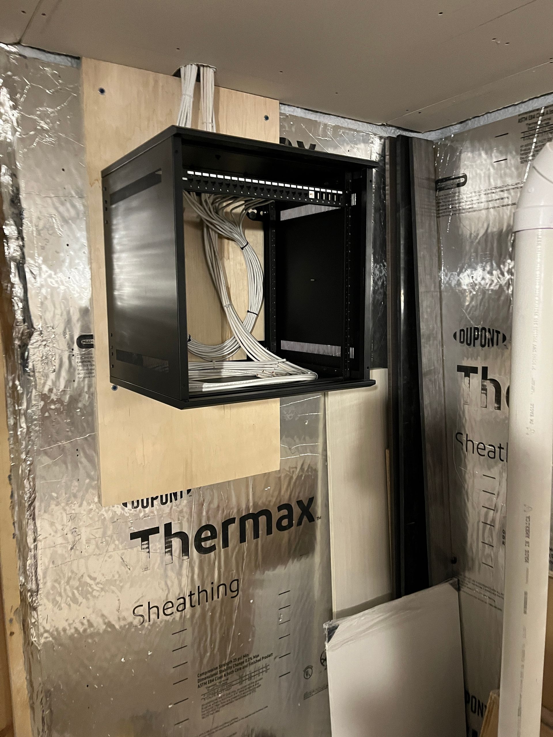 A black box is hanging on a wall next to a sign that says thermox.