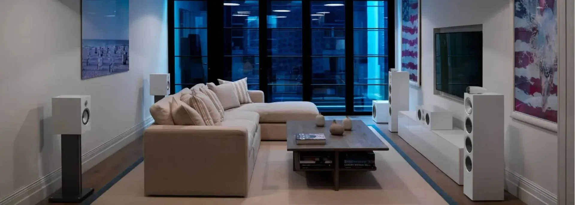 A living room with a couch , coffee table , speakers and a television.