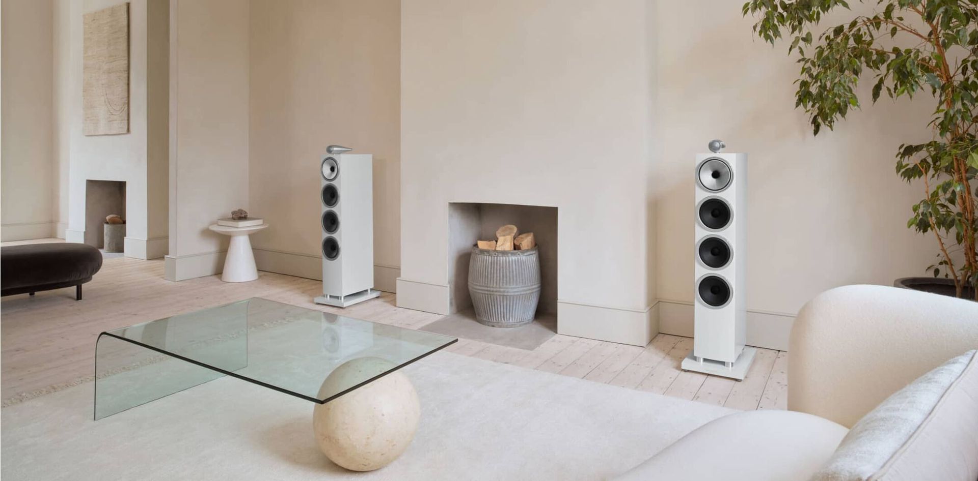 A living room with a couch , coffee table , speakers and a fireplace.