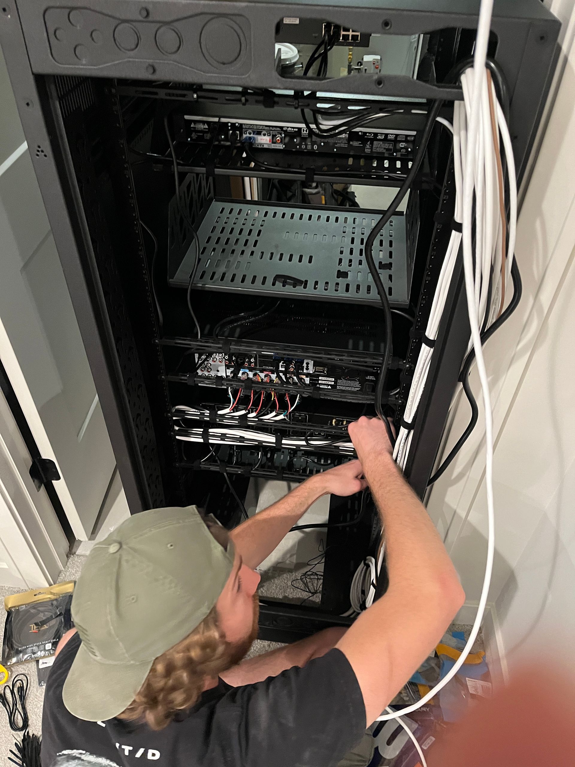 A man in a hat is working on a server rack.