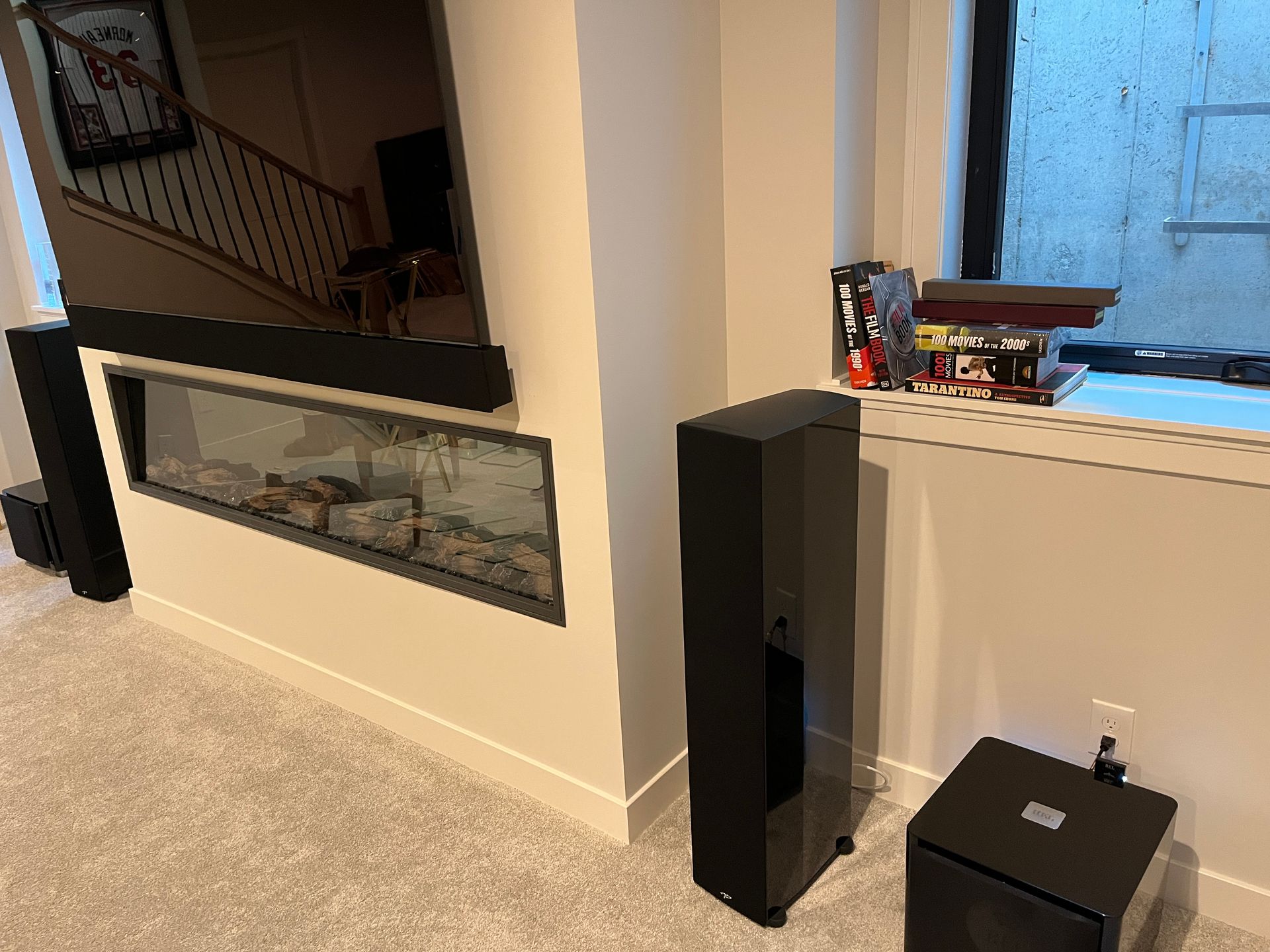 A living room with a fireplace , speakers , and a window.