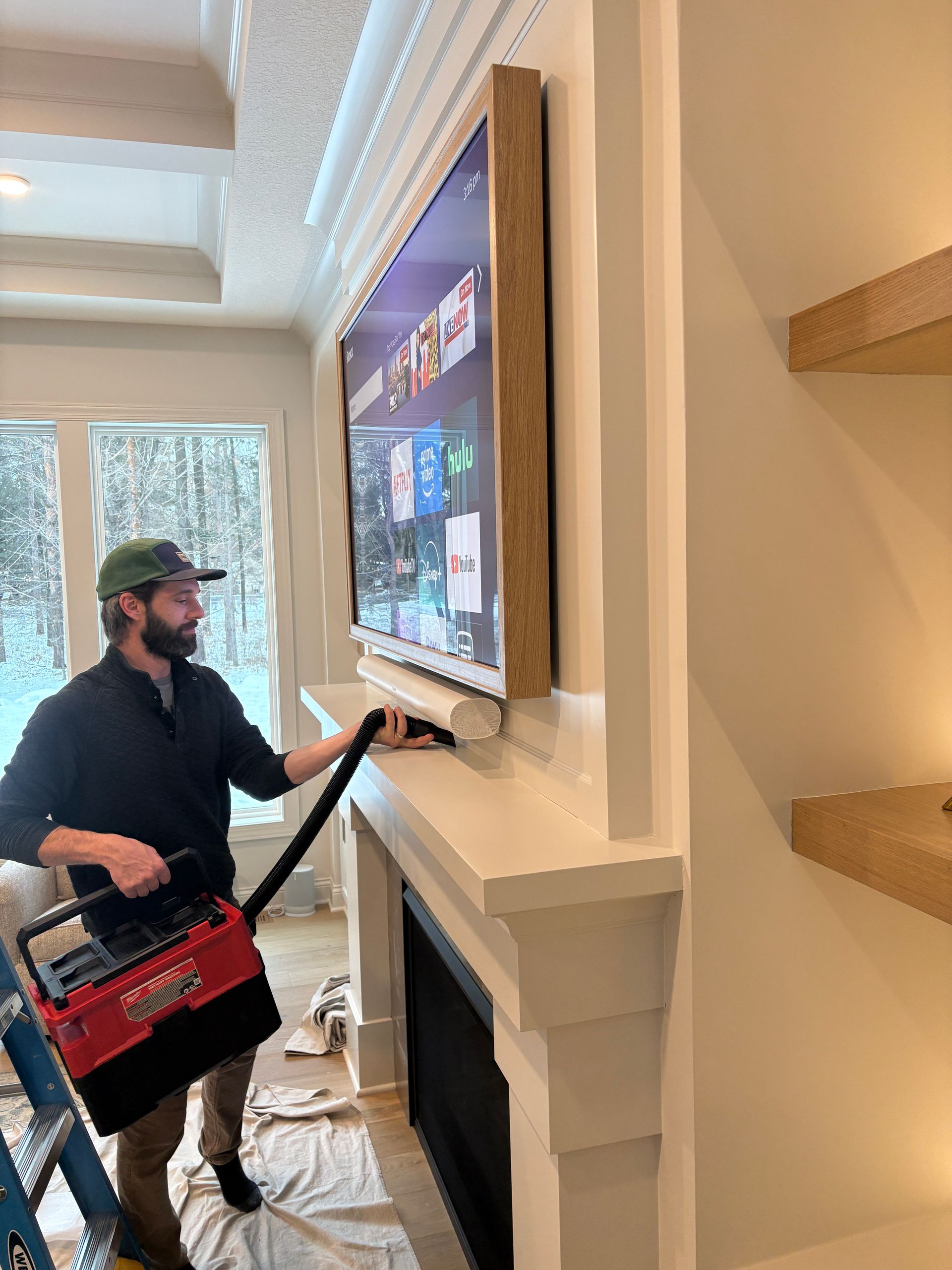 A man is cleaning a fireplace with a vacuum cleaner.