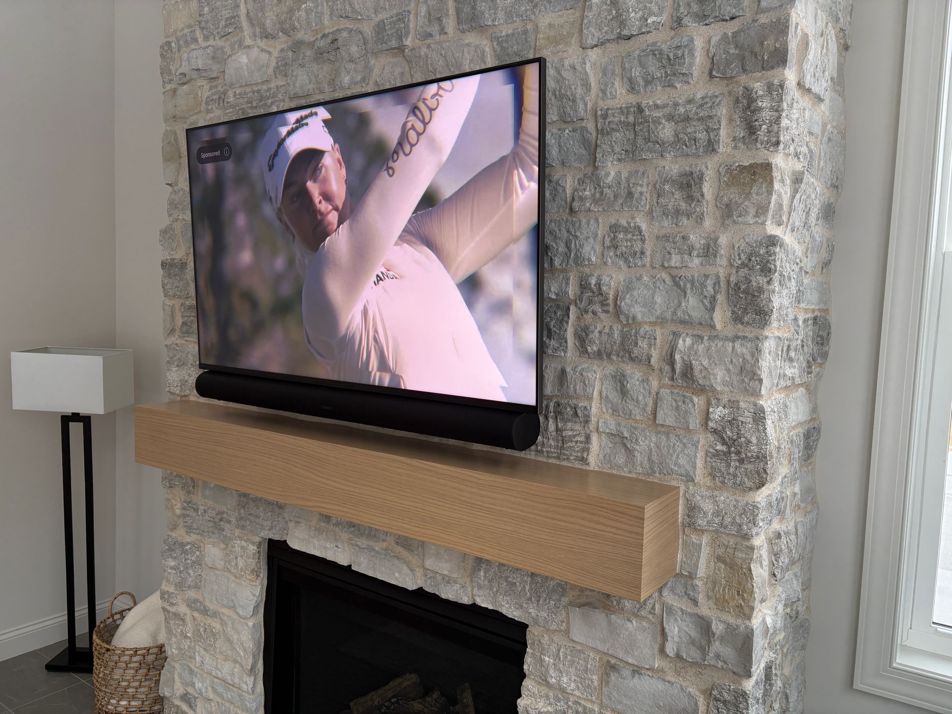 A flat screen tv is hanging over a fireplace in a living room.