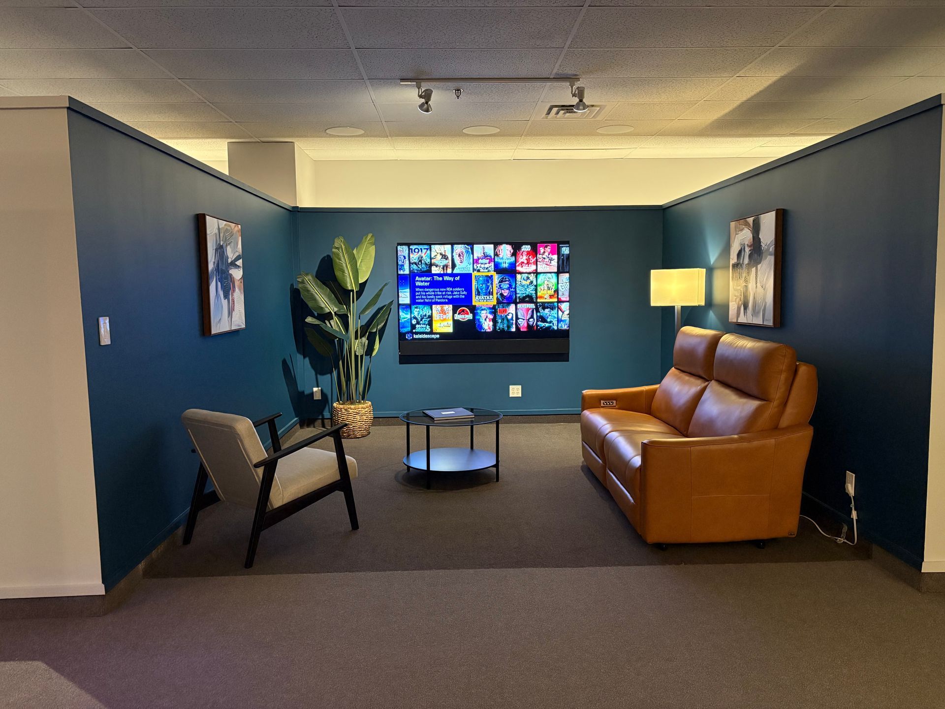 A living room with a couch and chairs and a flat screen tv on the wall.