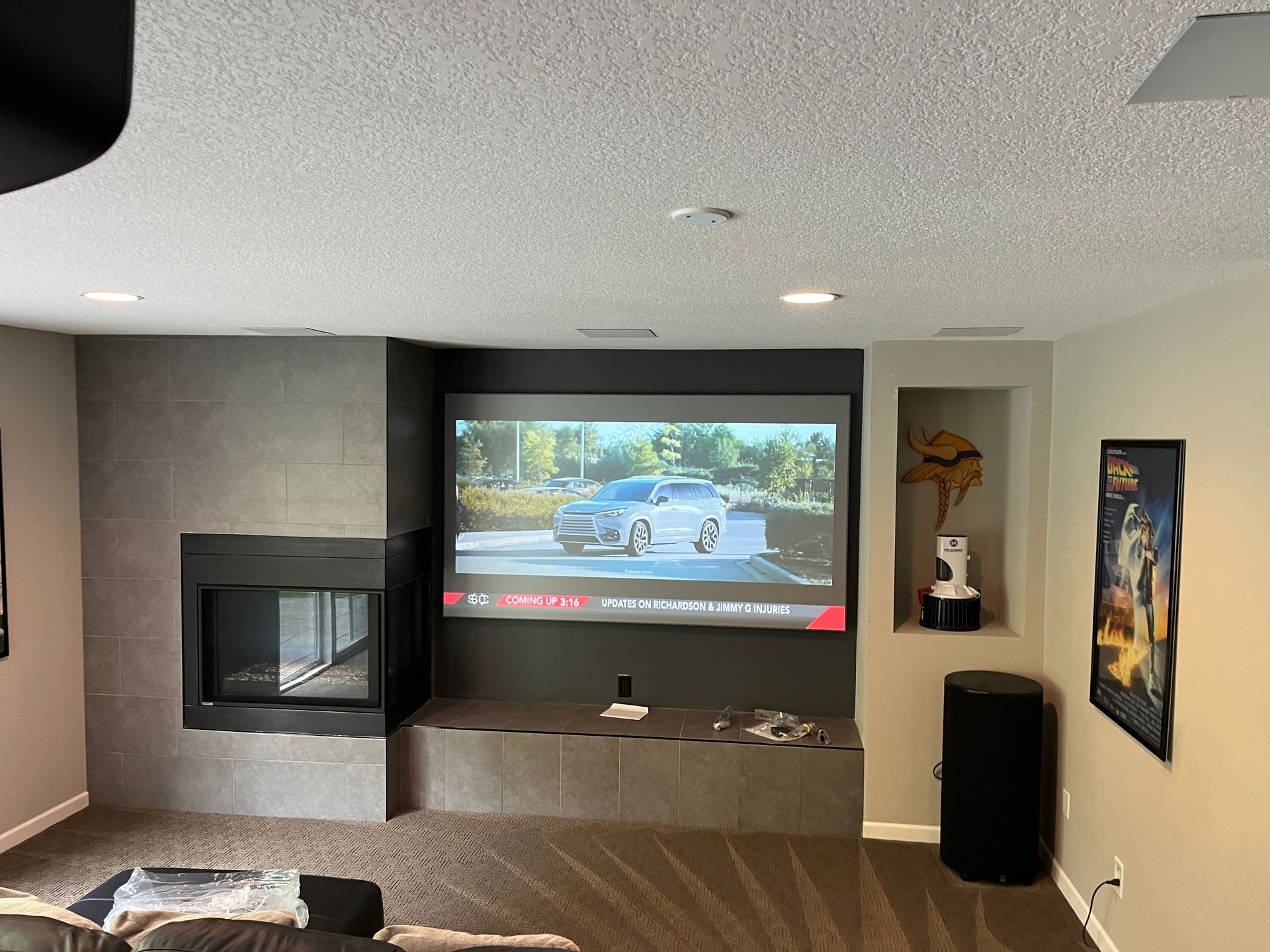 A living room with a projector screen and a fireplace