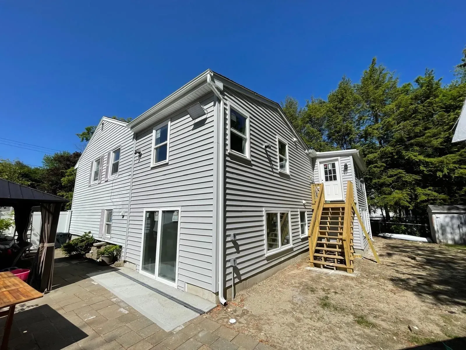 Two-story gray house with white trim; exterior staircase; sunny, blue sky.