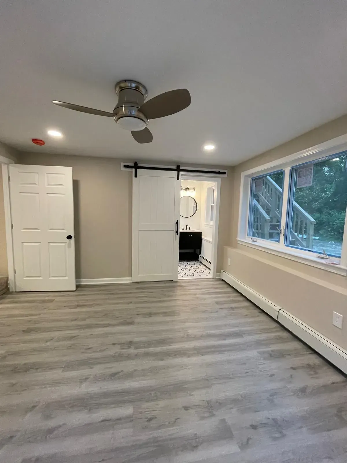 Bedroom with gray flooring, white door, and a sliding door to the bathroom.