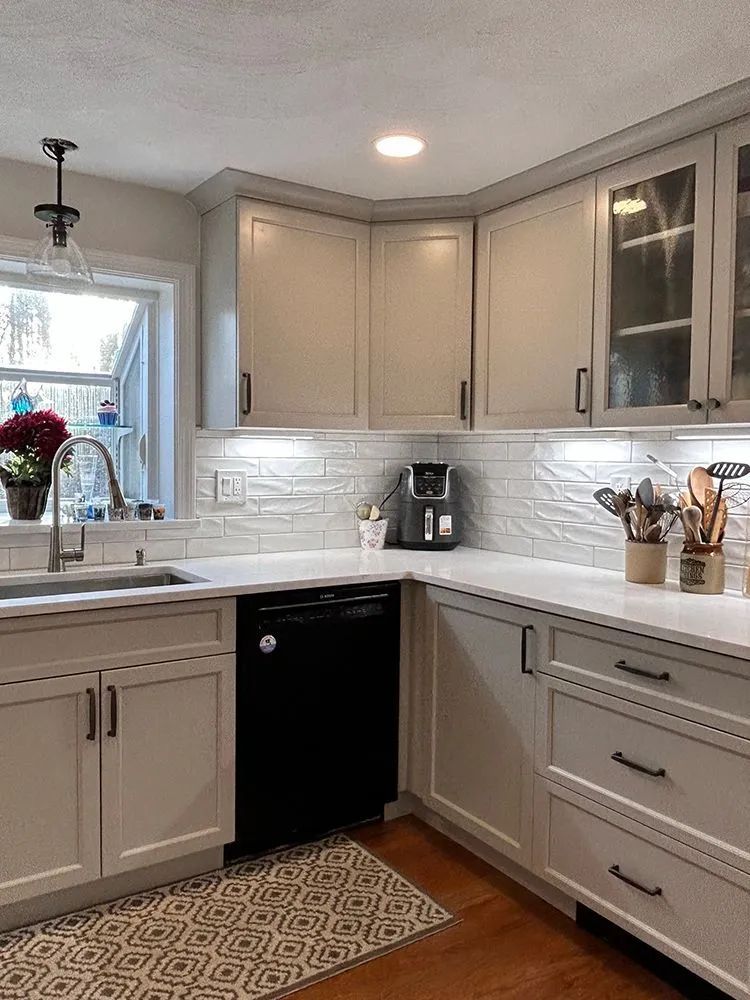 Kitchen with white cabinets, black dishwasher, and white countertops.