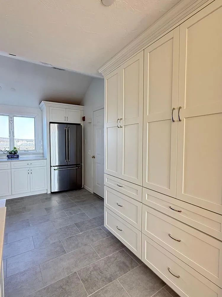 Kitchen with white cabinets, stainless steel refrigerator, and gray tiled floor.