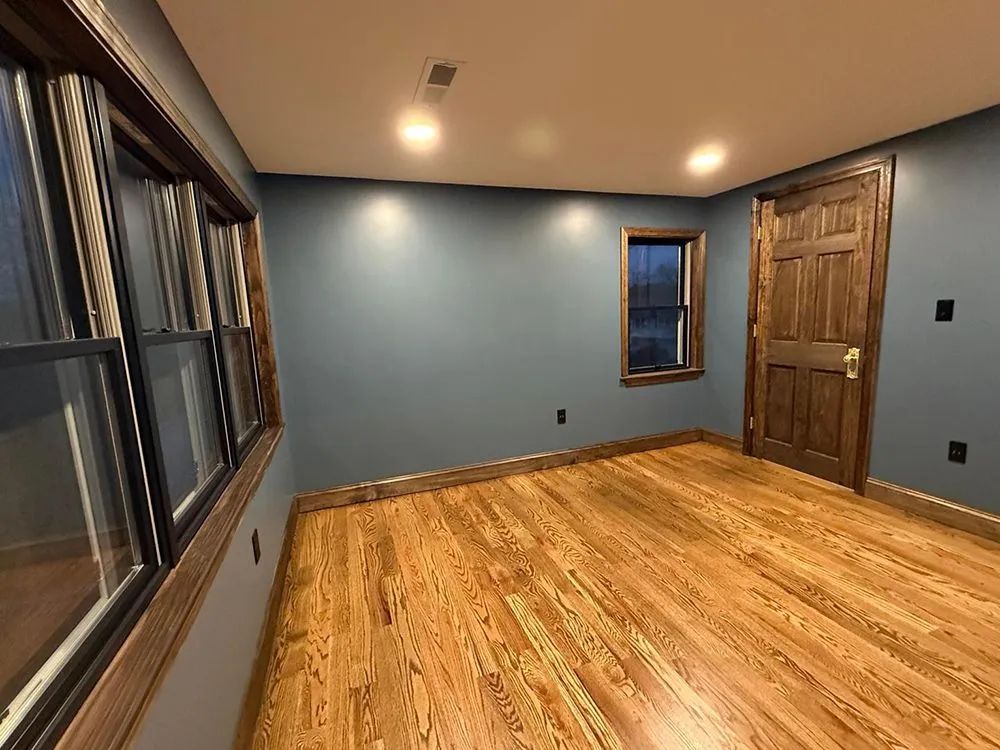 Empty room with hardwood floors, blue walls, and a wood door and trim.