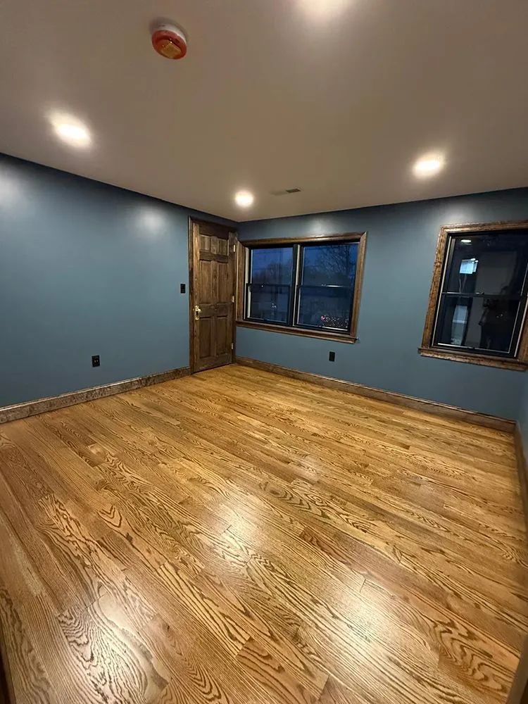 Room with wood floors, blue walls, and a wood door and window frames.