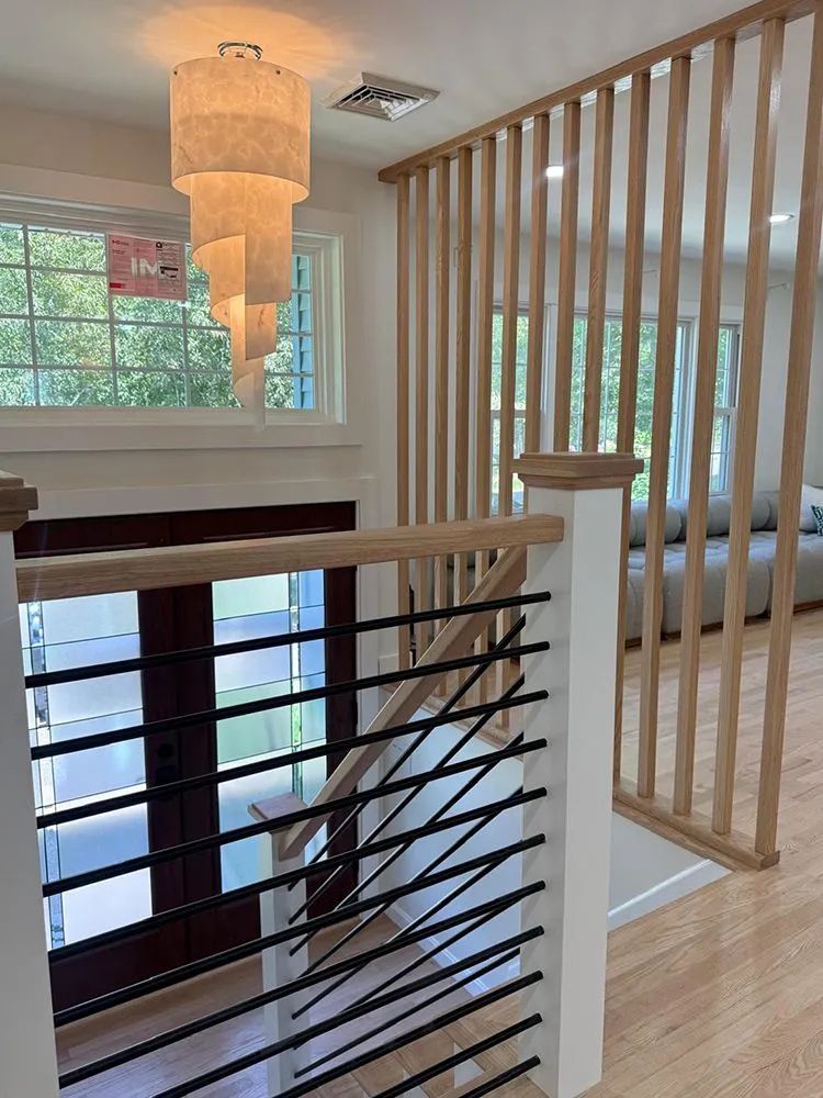 Interior with staircase, wooden slat wall, modern black railing, and decorative hanging light.