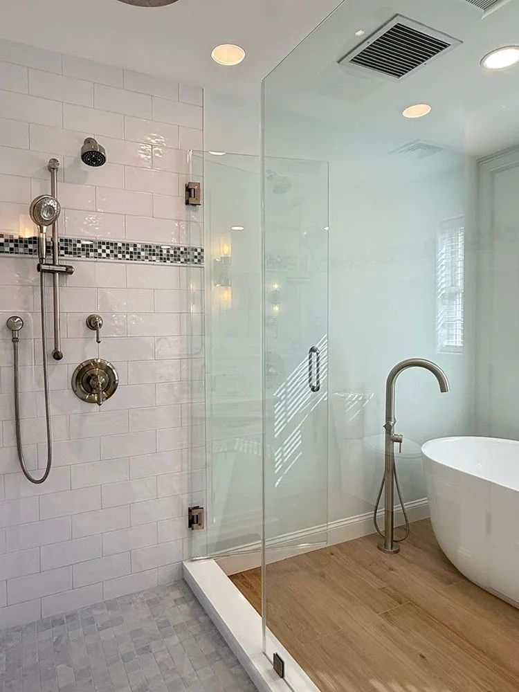 Bathroom with glass shower, white walls, wood floor, and freestanding tub.