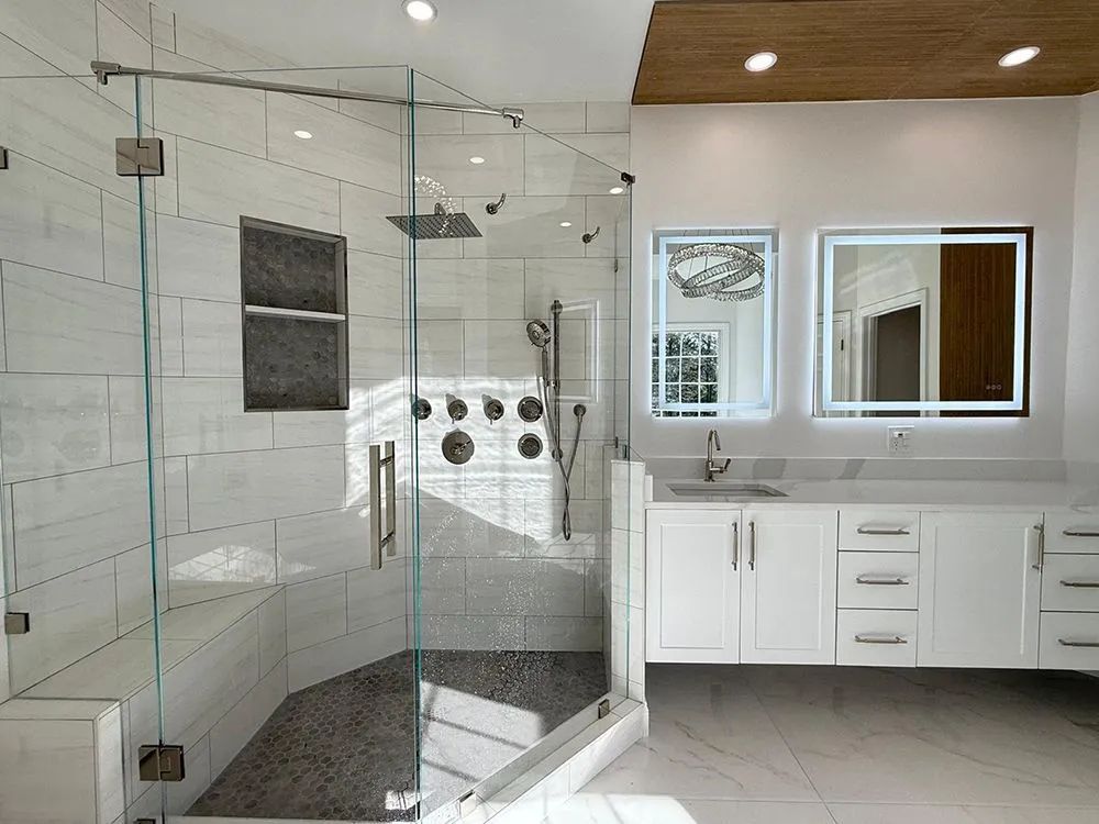 Modern bathroom with glass shower, white vanity, and rectangular mirrors.