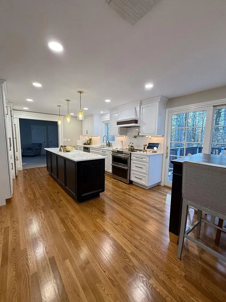 Kitchen with dark brown island and white cabinets, light wood floors, and recessed lighting.