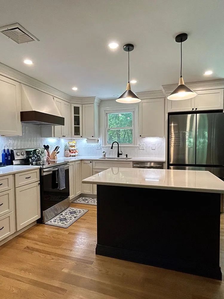 Modern kitchen with light cabinets, dark island, stainless steel appliances, and hardwood floors.